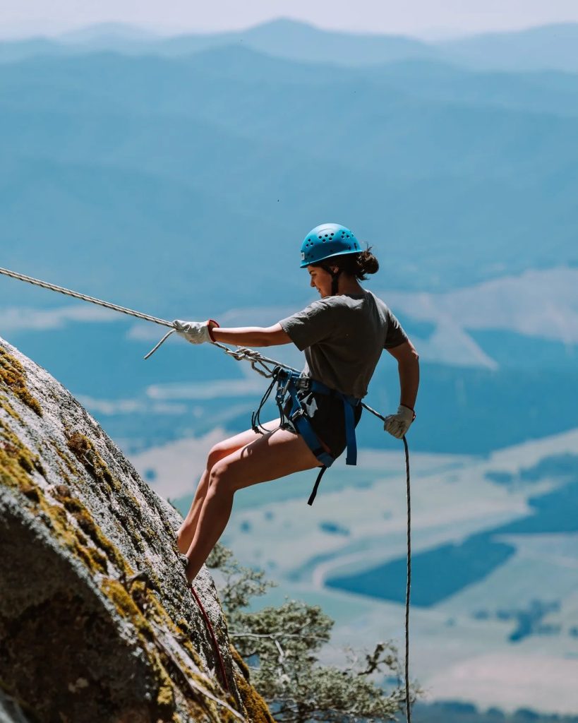 Participant abseiling down a cliff at Mount Buffalo under expert supervision